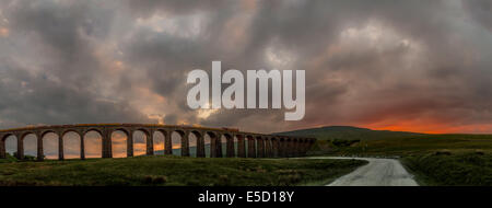 Scena creativa del rurale viadotto Ribblehead in una notevole tramonto con un treno crossing, Yorkshire Dales, England, Regno Unito Foto Stock