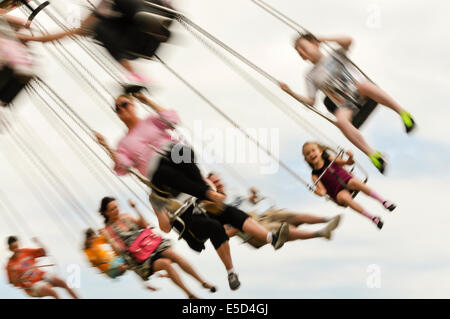 Molti bambini su un 'chairplane' ride (sfumata per mostrare la velocità) Foto Stock