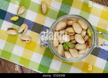 I pistacchi in vintage il vasetto di vetro sul panno a scacchi Foto Stock