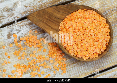 Di lenticchie rosse in ciotola di legno su una superficie di legno Foto Stock