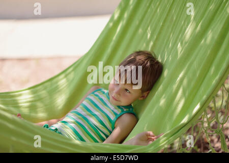 In estate il parco little boy in una camicia verde è in una amaca Foto Stock