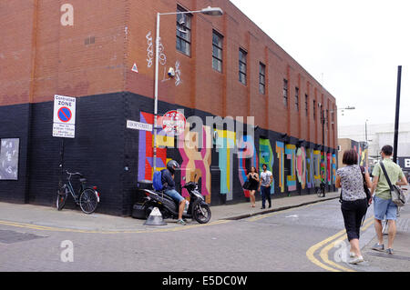 Uomo sospetti sul ciclomotore a guardare i turisti da angolo di strada in Shoreditch, Londra, Inghilterra Foto Stock