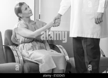 Donna paziente in 40s agitando la mano con il medico in ospedale in sala d'attesa prima di checkup. Foto Stock