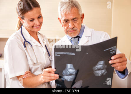 Senior medico maschio analisi MRI scan con il suo sorriso assistente femmina. Foto Stock