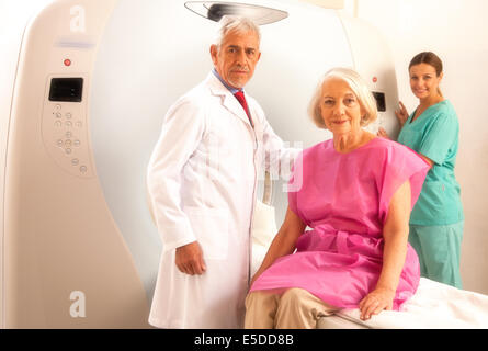 Donna in 60s pronto per essere controllato sotto scanner MRI con i senior medico e sorridente assistente femmina. Foto Stock