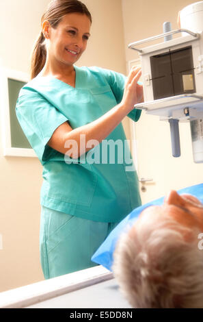 Senior uomo in 60s sottoposta a scansione a raggi x con femmina sorridente medico presso la macchina dello scanner. Foto Stock