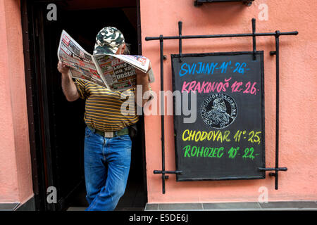 All'ingresso del bar Man che legge un giornale quartiere Zizkov di Praga. Offre quattro tipi di birra con menu a base di gesso Foto Stock