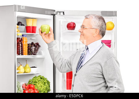 Senior uomo prendendo una mela da un frigorifero Foto Stock