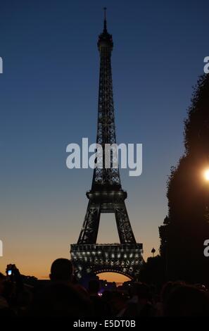 Torre Eiffel Parigi tramonto contro il cielo blu e nuvole rosso, luci bianco brillante su il grigio ferro battuto, turisti silhouette Foto Stock