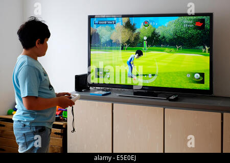 Giovane ragazzo giocando nella parte anteriore del grande schermo con nintendo wii a casa Foto Stock