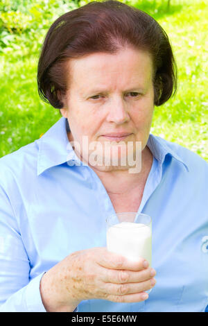 Senior donna tenendo un bicchiere di latte Foto Stock