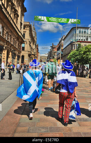 Glasgow, Scotland, Regno Unito. 28 Luglio, 2014. Giochi del Commonwealth sostenitori drappeggiati con la bandiera scozzese (si intraversa) e indossare pantaloni tartan a piedi attraverso un vivace Buchanan Street a Glasgow in un pomeriggio rovente come la febbre giochi inghiotte la città. Credito: PictureScotland/Alamy Live News Foto Stock