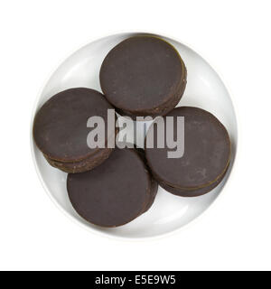 Vista dall'alto di diversi ricoperta di cioccolato snack dolci in un piccolo piatto su uno sfondo bianco. Foto Stock