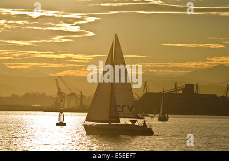 Barche a vela al tramonto sulla baia di Santander. In background, Santander porto commerciale può essere visto. Foto Stock