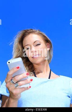 Una giovane donna con il suo telefono in una giornata di sole Foto Stock