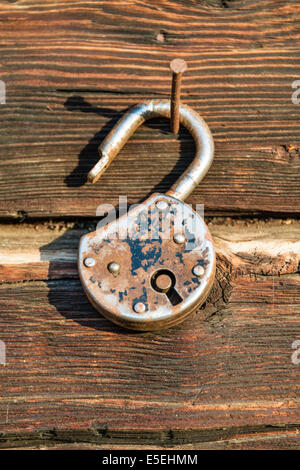 Vecchia serratura arrugginita appesa a un chiodo su una parete in legno Foto Stock