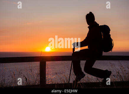 Il camminatore femmina all alba del Cleveland Way National Trail sentiero costiero 300ft sopra il livello del mare su scogli nelle vicinanze del Saltburn. Regno Unito Foto Stock