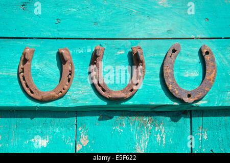 Tre Vecchi rusty Il ferro di cavallo su una vecchia porta di legno - simbolo di fortuna Foto Stock