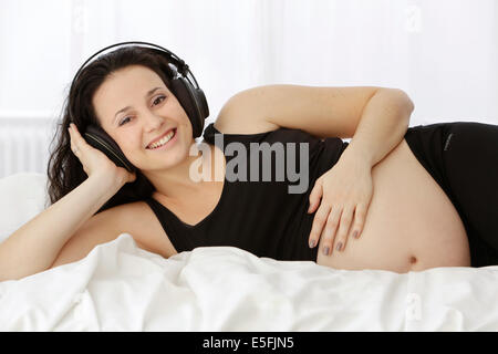 Donna incinta ascoltando musica Foto Stock