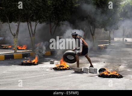 Sanaa, Yemen. Il 30 luglio, 2014. Un yemenita brucia pneumatici per protestare contro la decisione del governo di aumentare drasticamente il prezzo del carburante in Sanaa, Yemen, il 30 luglio 2014. Il governo yemenita ha aumentato il prezzo della benzina da 125 yemenita riyals (0,58 dollari USA) a 200 riyals per litro e disel da 100 riyals a 195 riyals Mercoledì, che ha scatenato proteste di massa nella capitale Sanaa. Manifestanti arrabbiati pneumatici bruciati e tagliato molte strade in Sanaa. Il governo ha distribuito più soldati per mantenere la sicurezza nella capitale. Credito: Mohammed Mohammed/Xinhua/Alamy Live News Foto Stock