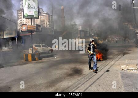 Sanaa, Yemen. Il 30 luglio, 2014. Un yemenita brucia pneumatici per protestare contro la decisione del governo di aumentare drasticamente il prezzo del carburante in Sanaa, Yemen, il 30 luglio 2014. Il governo yemenita ha aumentato il prezzo della benzina da 125 yemenita riyals (0,58 dollari USA) a 200 riyals per litro e disel da 100 riyals a 195 riyals Mercoledì, che ha scatenato proteste di massa nella capitale Sanaa. Manifestanti arrabbiati pneumatici bruciati e tagliato molte strade in Sanaa. Il governo ha distribuito più soldati per mantenere la sicurezza nella capitale. Credito: Mohammed Mohammed/Xinhua/Alamy Live News Foto Stock