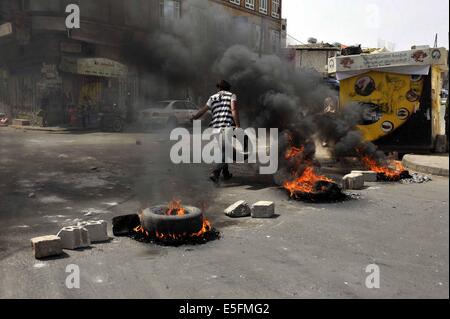 Sanaa, Yemen. Il 30 luglio, 2014. Un yemenita brucia pneumatici per protestare contro la decisione del governo di aumentare drasticamente il prezzo del carburante in Sanaa, Yemen, il 30 luglio 2014. Il governo yemenita ha aumentato il prezzo della benzina da 125 yemenita riyals (0,58 dollari USA) a 200 riyals per litro e disel da 100 riyals a 195 riyals Mercoledì, che ha scatenato proteste di massa nella capitale Sanaa. Manifestanti arrabbiati pneumatici bruciati e tagliato molte strade in Sanaa. Il governo ha distribuito più soldati per mantenere la sicurezza nella capitale. Credito: Mohammed Mohammed/Xinhua/Alamy Live News Foto Stock