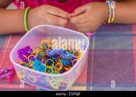 'Telaio bande' hobby contenitore molti colori variopinti mani rendendo bracciale bambino ragazza closeup Foto Stock