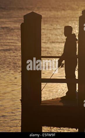 Silhouette di uomo di pesca sul molo al tramonto alle barene, Dorset in luglio Foto Stock