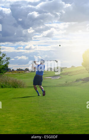 Maschio di giocatore di golf di rinvio off pallina da golf dalla scatola a t al tramonto Foto Stock