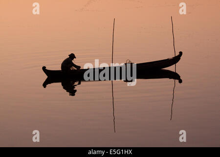 Un pescatore in una canoa di legno sul lago Taungthaman all'alba, Amarapura, Mandalay regione, Myanmar (Birmania) Foto Stock