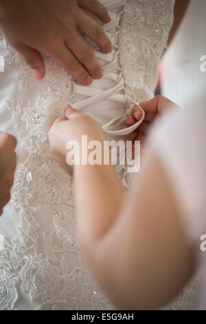 Bridesmaids aiutando con un abito da sposa su un giorno di nozze Foto Stock