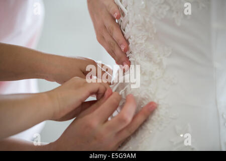 Bridesmaids aiutando con un abito da sposa su un giorno di nozze Foto Stock