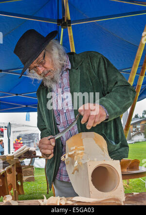 Intagliare la "avvisatore acustico di un figlio Beat da un blocco solido di legno. Una leggera sfocatura di movimento sul carver le mani Foto Stock