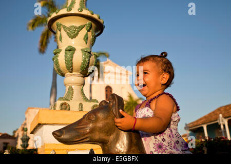 Ridere piccola ragazza su un cane statua statua di fronte alla cattedrale e alla piazza Plaza Mayor in Trinidad, Cuba, Caraibi Foto Stock