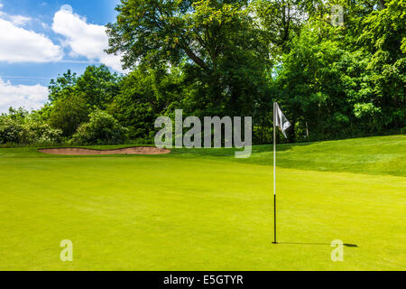 Un bunker e putting green con flagstick e foro su un tipico campo da golf. Foto Stock