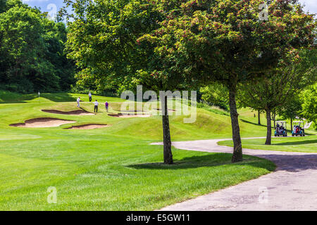 Quattro maschi golfisti giocare vicino al bunker su un campo da golf. Foto Stock