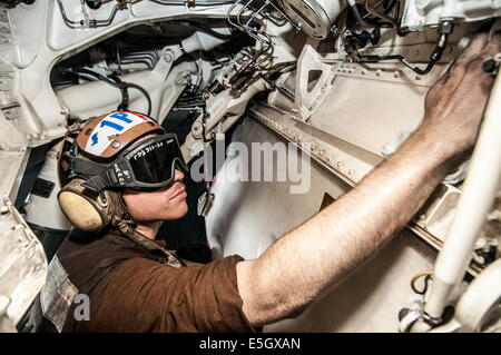 Stati Uniti Aviazione Navale meccanico strutturale di terza classe Ryan Reid pulisce l'atterraggio principale ruota dentata e di un F/A-18F Super Hornet un Foto Stock