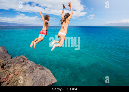 Amici cliff jumping nell'oceano, estate divertimento stile di vita. Foto Stock