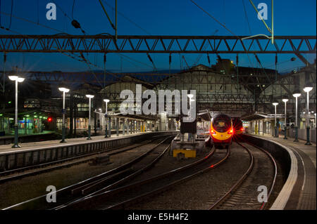 La fine delle piattaforme della stazione ferroviaria di Manchester Piccadilly durante la serata tra cui una vergine treno pendolino. Foto Stock