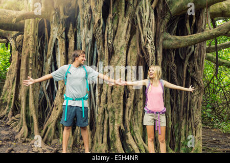 Attraente coppia giovane divertendosi insieme all'aperto sulla passeggiata, in piedi nella parte anteriore del gigante banyan tree. Foto Stock