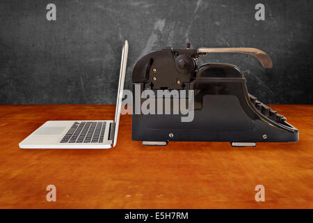 Argento Moderno laptop e una vecchia macchina da scrivere nero su un tavolo di legno Foto Stock
