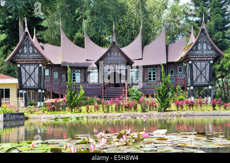 Rumah gadang nel Pandai Sikek villaggio di Sumatra Occidentale, con due fienili di riso (rangkiang) davanti. Foto Stock