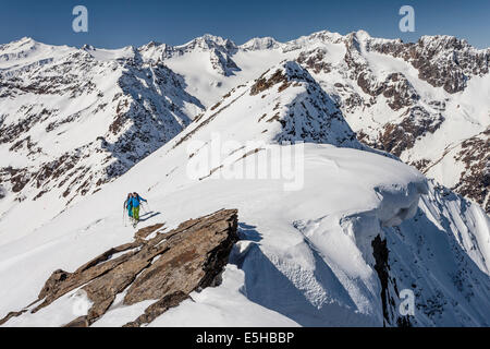 Ski walkers sul crinale del vertice con il cumulo di neve, salita al Laaser Spitze in Val Martello, dietro il gruppo del Ortles con Foto Stock