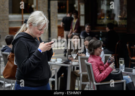 British blonde donna bianca della legge invia un messaggio di testo sms posta elettronica su uno smartphone smart phone. Foto Stock