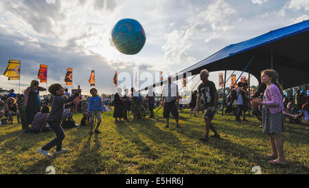 Malmesbury, Regno Unito, 25/07/2014 : Atmosfera al WOMAD - un mondo di musica, arte e danza. Una famiglia gioca con un globo gonfiabile nella luce della sera. Foto di Julie Edwards Foto Stock