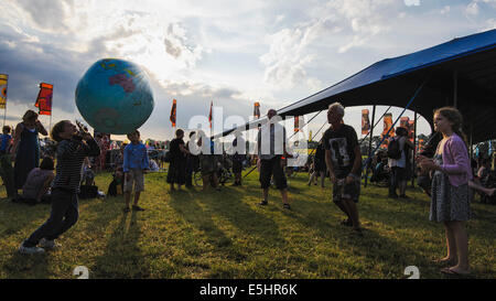 Malmesbury, Regno Unito, 25/07/2014 : Atmosfera al WOMAD - un mondo di musica, arte e danza. Una famiglia gioca con un globo gonfiabile nella luce della sera. Foto di Julie Edwards Foto Stock