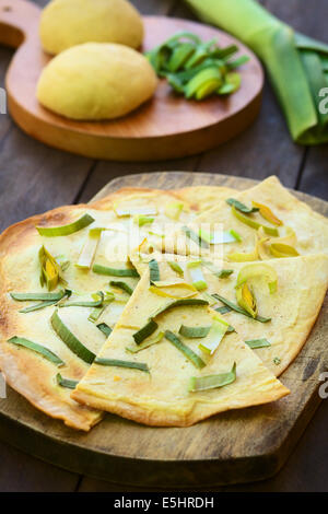 Vegetariano francese Tarte Flambee in sottile di pasta di pane con una crema di porri e topping, servita su tavola di legno con ingredienti Foto Stock