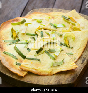 Vegetariano francese Tarte Flambee in sottile di pasta di pane con una crema di porri e topping, servita sulla tavola di legno Foto Stock