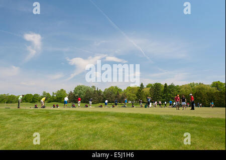 Gli amanti del golf a migliorare il loro swing su un driving range. Foto Stock