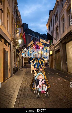 Paesi Bassi, Maastricht, festa di carnevale. Costume uomo a camminare con sua figlia in baby car. Twilight Foto Stock